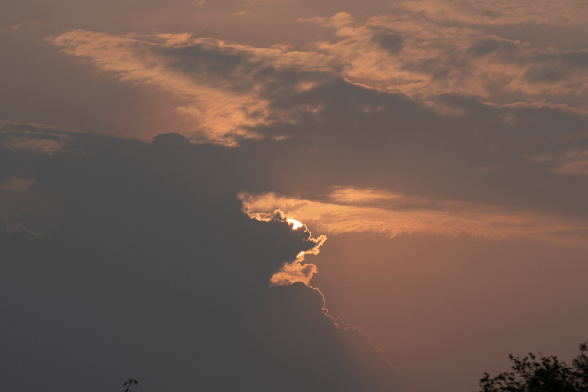 Sunset sky with clouds and warm light breaking through over the landscape.