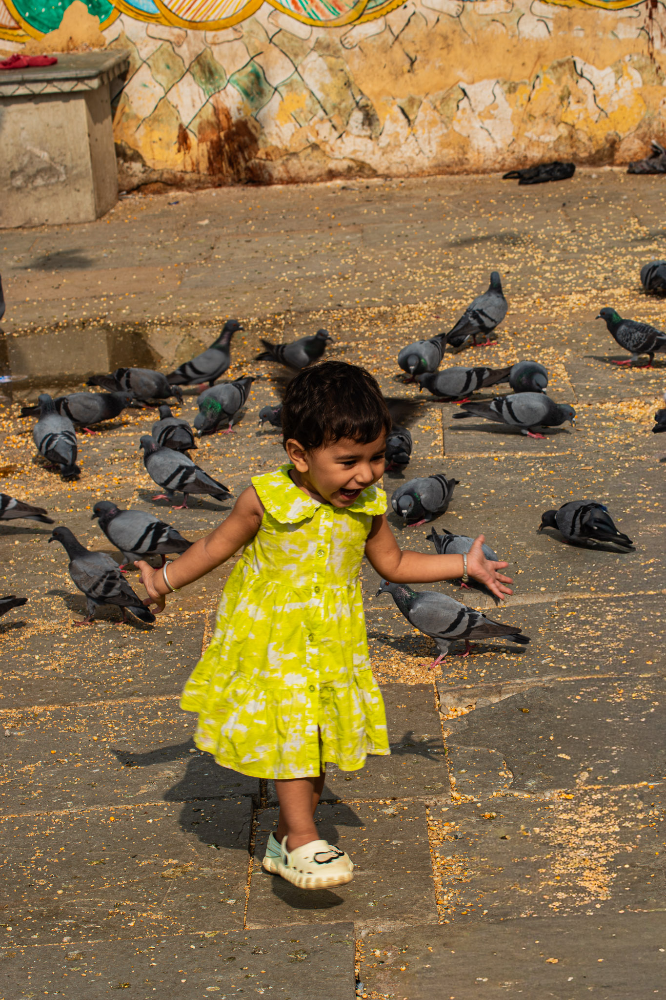 Child jumping with arms wide in a candid street photograph titled A Moment Of Freedom.
